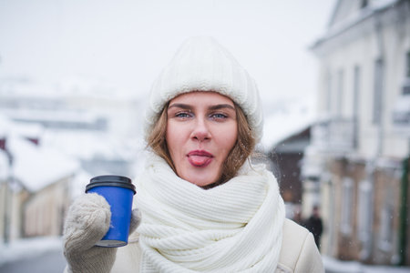 Beautiful and stylish girl model posing for a photographer on a city street in winter