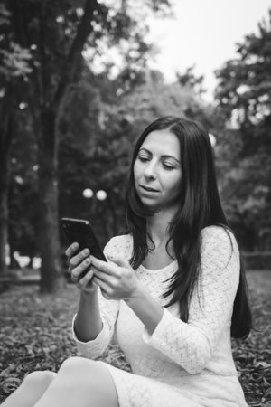 Beautiful brunette girl in autumn park talking on a mobile phoneの写真素材