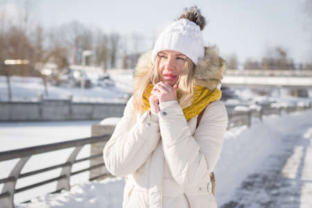 Beautiful blonde girl in white clothes in winter on a city street