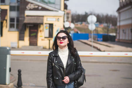 A beautiful hipster girl with a phone in her hands walks down the streetの写真素材