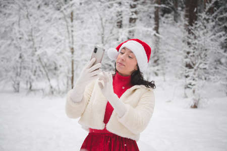 Beautiful girl in winter snowy forest in christmas clothes portraitの写真素材