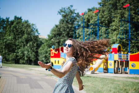 A beautiful Russian girl walks in the city park in the summer and rejoices