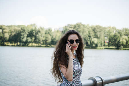 A beautiful Russian girl walks in the city park in the summer and rejoices