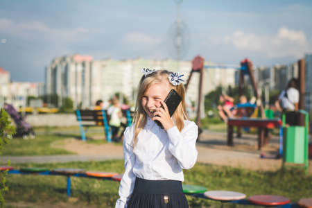 Little girl on the street talking on the phone and writing a message on the playgroundの写真素材