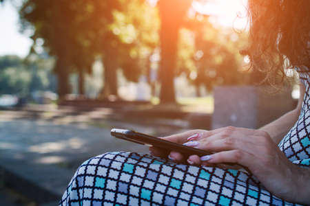 Woman hands using smartphone at sunset outsideの写真素材
