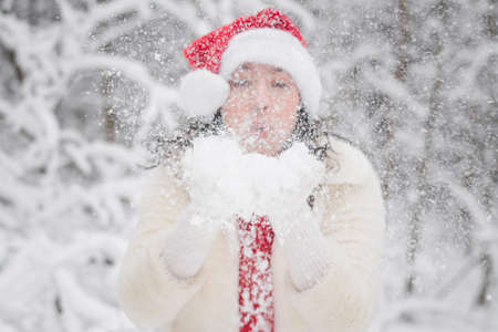 Beautiful girl in a snowy forest in Christmas clothesの写真素材