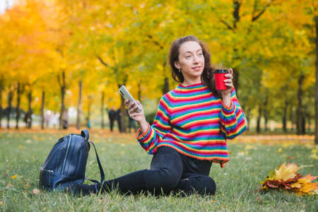 Young woman portrait on grass in autumn parkの写真素材