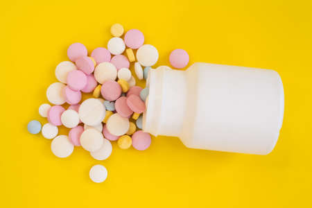 Colored pills for toothache or minstrual pain on yellow backgroundの写真素材