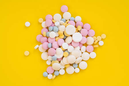 Colored pills for toothache or minstrual pain on yellow backgroundの写真素材