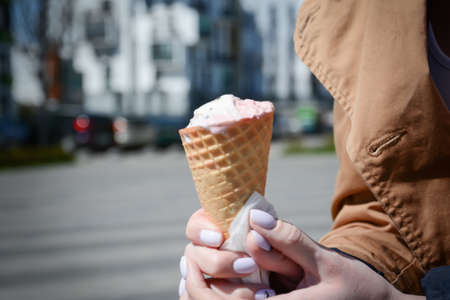 Ice cream in a wafer cup in a woman's hands in the city