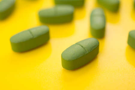 Green cold pills on a yellow backgroundの写真素材