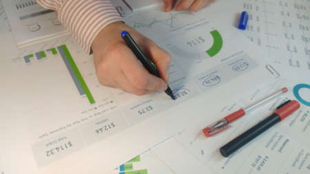Male Hand is checking with marker list of business figures in the office 4k stock footage top view
