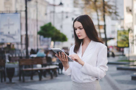 Portrait of caucasian businesswoman using tablet pc outside