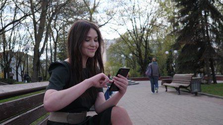 beautiful young woman with a phone in her hands on the street of her cityの写真素材