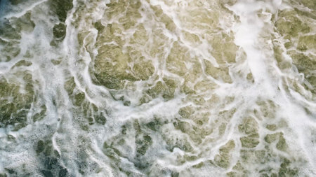 An impressive overhead shot that beautifully captures the dynamic and intricate patterns of ocean waves and their foamの写真素材