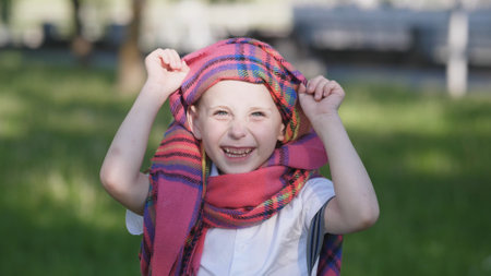 A Joyful Child is Happily Playing Outdoors While Wearing a Colorful Scarf in Natureの写真素材