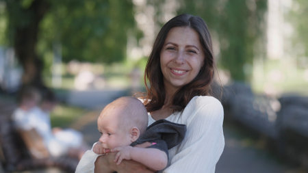 A Joyful Mother Holding Her Baby in a Beautiful Natural Setting Amidst the Outdoorsの写真素材