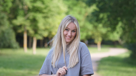 A Smiling Young Woman in Nature Who is Surrounded by Beautiful Lush Greenery and Plantsの写真素材
