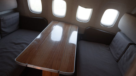 Vintage Interior of a Soviet-era Aircraft Showcasing a Wooden Table and Cozy Seating Arrangement With Multiple Windowsの写真素材