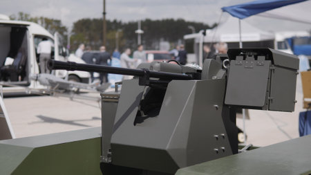 Attendees explore a military technology exhibit featuring a modern weapon system, displaying innovation and engineering in defense applications.の写真素材