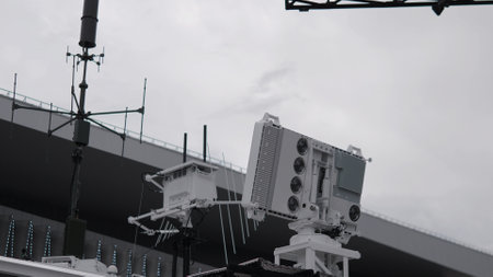 Complex surveillance equipment is positioned atop infrastructure, designed for monitoring urban areas while adapting to the cloud-covered sky.の写真素材