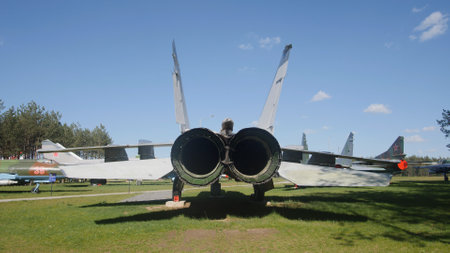 A military fighter jet showcases its design with rear-facing engines against a backdrop of blue skies, located in a lively park during an aviation event.の写真素材