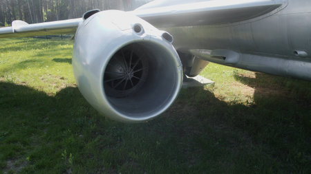 An aircraft jet engine rests on the grass, showcasing its detailed components and metallic exterior...