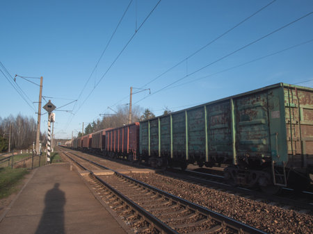 A Freight Train is patiently waiting at the Station while the clear blue sky shines above