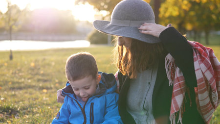 Mother and Son Enjoying a Sunny Afternoon in the Park With Vibrant Foliage During Early Autumn