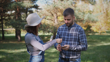 Friends Engaging in an Outdoor Conversation While Exchanging Plants, Surrounded by Lush Greenery on a Sunny Day in the Parkの写真素材