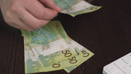 Closeup Hands Sorting Fifty Zloty Bills Near Keyboard, Retail Checkout Vibe With Deliberate...