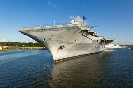 The World War II era aircraft carrier USS Yorktown, docked in the Charleston, SC Harbor with dramatic blue skies and reflections in the waterのeditorial素材
