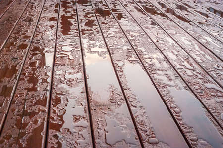Pooled water on finished deck with woodgrain. Excellent background for illustrating construction or resilience.の写真素材