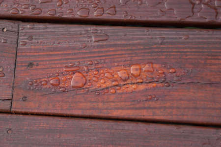 Pooled water on finished deck with woodgrain. Excellent background for illustrating construction or resilience.の写真素材