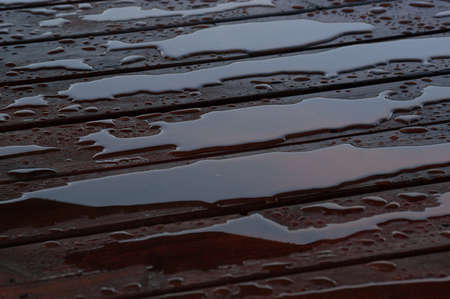 Pooled water on finished deck with woodgrain. Excellent background for illustrating construction or resilience.の写真素材