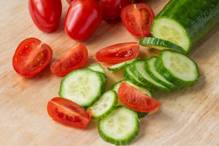 Sliced cucumber and cherry tomatoes - wood backgroundの写真素材