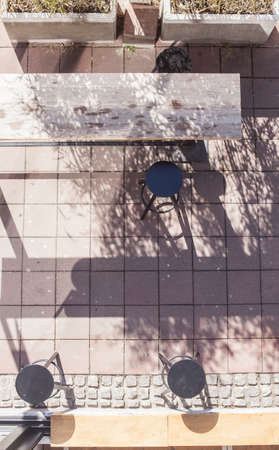 Bar stool, wooden table on a street pavementの写真素材