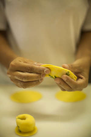 Human Hands making Raw and dry capeletti pasta on kitchen tableの写真素材