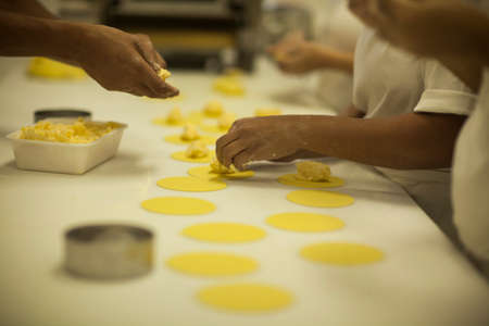 Human Hands making Raw and dry capeletti pasta on kitchen tableの写真素材