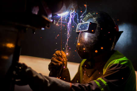 Man works on metal welding steel using electric welding machine to weld.の写真素材