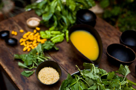 Amazonian cuisine. Green ingredients, manioc soup on a wooden table set. high quality photoの写真素材