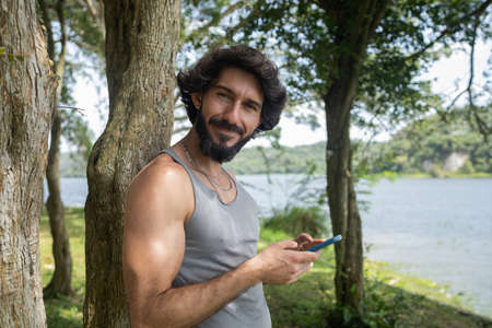 Young man at a park on a beautiful sunny day with laptop on his lap. Gray notebook for working and leisure. Home office concept. Green and nature background. high quality photoの写真素材