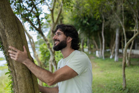 Young man at a park on a beautiful sunny day with mobile phone. Mobile phone for working and leisure. Home office concept. Green and nature background. high quality photoの写真素材
