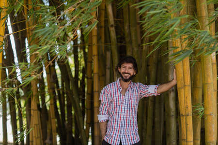 Young man at a park on a beautiful sunny day with mobile phone. Mobile phone for working and leisure. Home office concept. Green and nature background. high quality photoの写真素材