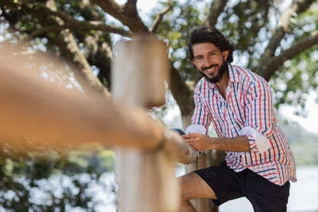 Young man at a park on a beautiful sunny day with mobile phone. Mobile phone for working and leisure. Home office concept. Green and nature background. high quality photoの写真素材