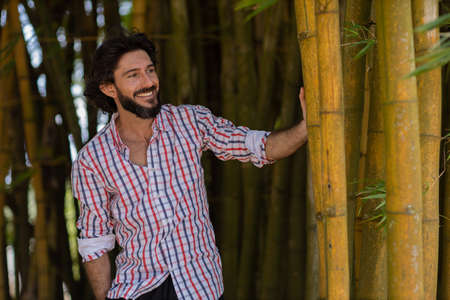 Portrait of smiling young man at a park on a beautiful sunny day. Green and nature background. Bamboo forest. high quality photoの写真素材