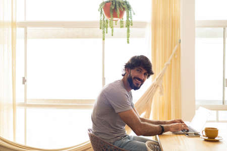 Young business man working at home in his kitchen with laptop and papers on kitchen wooden desk. Gray notebook for working. Home office concept. high quality photoの写真素材