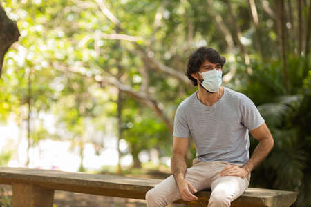 View of young man using a smartphone at day time with a green park in the background. Mobile phone, technology, urban concept. high quality photoの写真素材