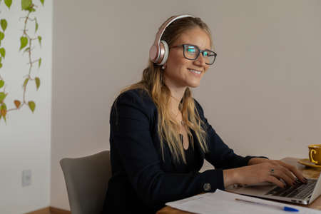 Young woman working at home with laptop and papers on desk and headphones. Home office concept. Gray notebook for working. high quality photoの写真素材
