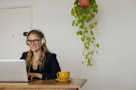 Young woman working at home with laptop and papers on desk and headphones. Home office concept. Gray notebook for working. high quality photoの写真素材